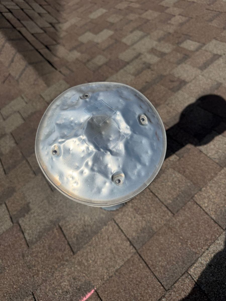 Metal roof vent cap covered in hail dents